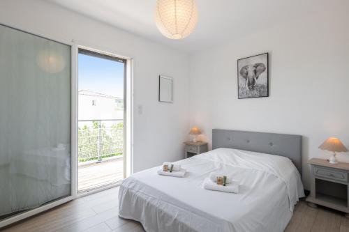 une chambre blanche avec un lit et une fenêtre dans l'établissement Maison Janas - Welkeys, à La Seyne-sur-Mer