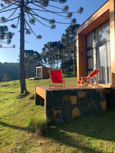 two red chairs sitting on a porch of a cabin at Estalagem Santa Clara in Urubici