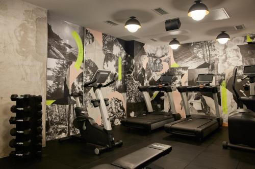 a gym with tread machines and a wall with a mural at Ace Hotel Toronto in Toronto
