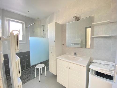 une salle de bain blanche avec un lavabo et un miroir dans l'établissement Maison rénovée, jardin clos, à 300m de la mer - 6 couchages, WiFi, animaux admis - FR-1-231-205, à Bretignolles-sur-Mer