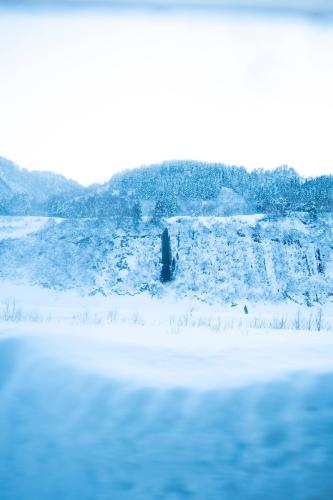 a snow covered field with a body of water at 古民家宿Tani House Itaya -セルフチェックイン in Tokamachi