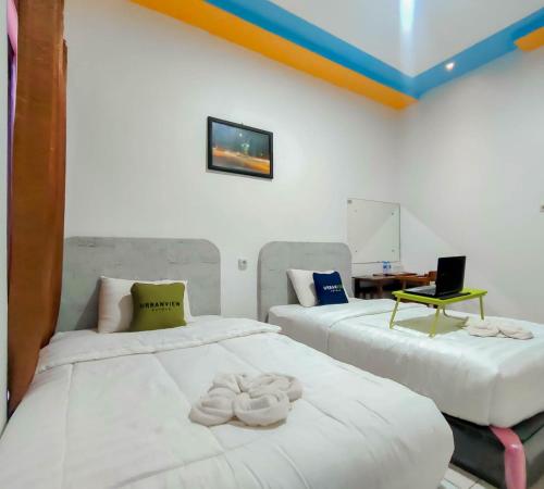 two beds sitting next to each other in a room at Urbanview Hotel Bagoes Sintang by RedDoorz in Sintang
