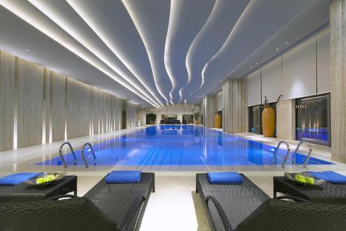 a large swimming pool with chairs in a building at Wanda Vista Dongguan in Dongguan