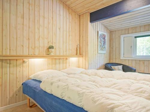 a bedroom with wooden walls and a large bed at Holiday home Nexø XLI in Vester Sømarken