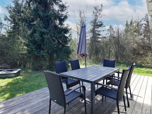 a wooden table with chairs and an umbrella on a deck at 10 person holiday home in Fjerritslev-By Traum in Fjerritslev