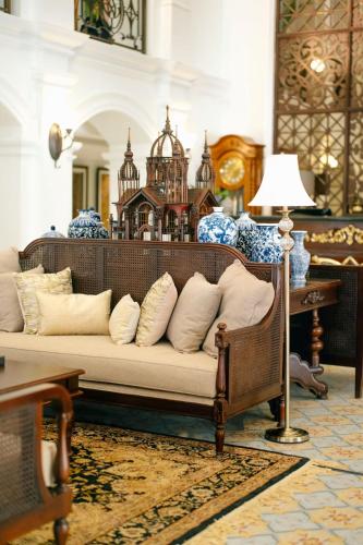 a living room with a couch with pillows at MAHALAYA The Legacy Hotel in Solo