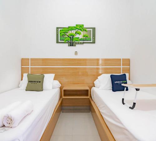 two beds in a room with a table at Urbanview Hotel Bundaran Besar Palangkaraya by RedDoorz in Palangkaraya