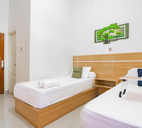 a bedroom with two beds with white sheets at Urbanview Hotel Bundaran Besar Palangkaraya by RedDoorz in Palangkaraya