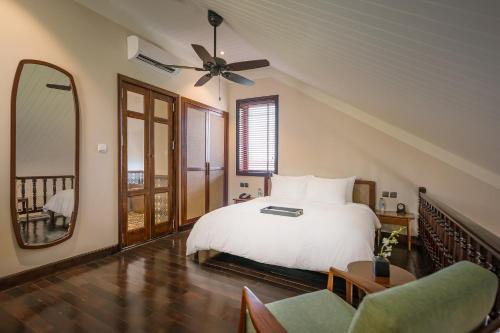 a bedroom with a white bed and a ceiling fan at La Siesta Hoi An Resort & Spa in Hoi An