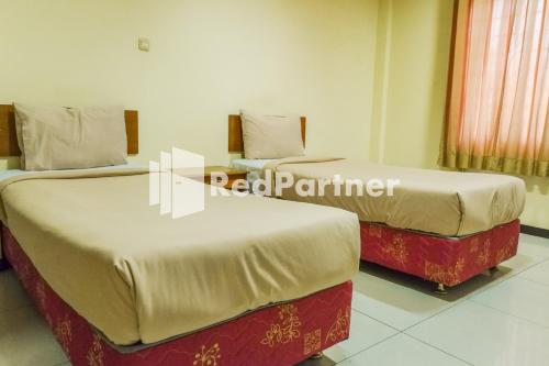 duas camas sentadas uma ao lado da outra num quarto em Grand Kembar Hotel Mitra RedDoorz em Bandung