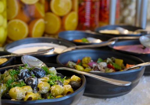 a bunch of dishes of food in pans with spoons at Holiday Inn Chennai OMR IT Expressway by IHG in Chennai