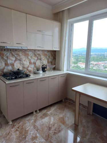 a kitchen with white cabinets and a stove and a window at Panorama Kutaisi in Kutaisi