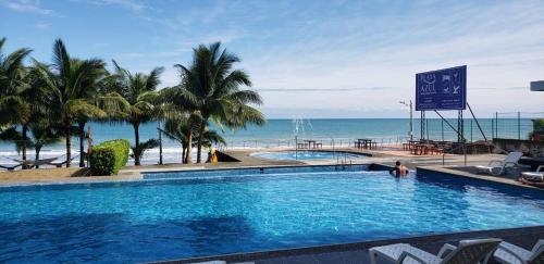 a swimming pool next to a beach with the ocean at Suite de Lujo en Resort Playa Azul, Tonsupa in Tonsupa