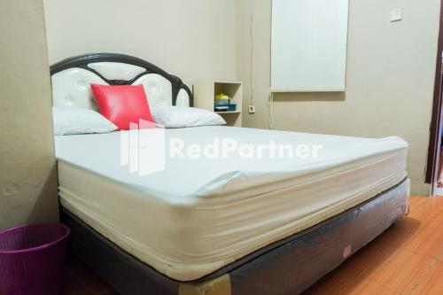 a bed in a room with a red pillow on it at Penginapan Rio Anakku Syariah Banjaran Mitra RedDoorz in Pameungpeuk