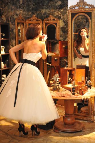 a woman in a dress brushing her teeth in front of a mirror at Leventis Art Suites in Panayítsa