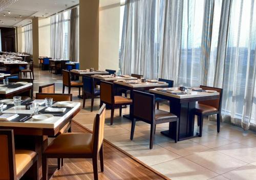a dining room with tables and chairs and windows at Holiday Inn Chennai OMR IT Expressway by IHG in Chennai