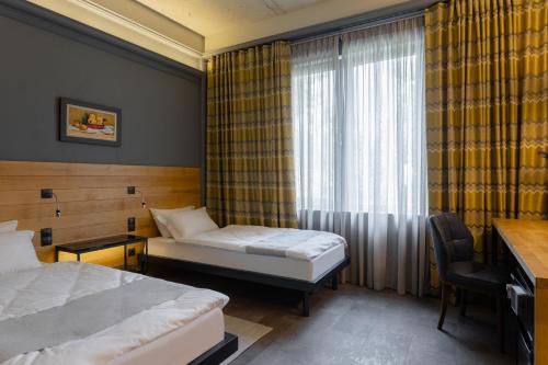 Cette chambre comprend 2 lits et une fenêtre. dans l'établissement Plai Hotel, à Chişinău