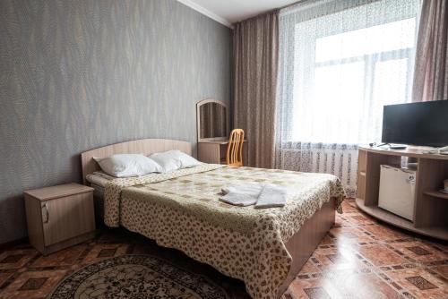 a small bedroom with a bed and a television at Гостиница Караганда in Karagandy