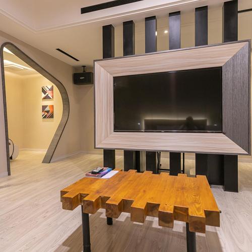a living room with a large tv and a wooden table at Soho Motel in Taoyuan