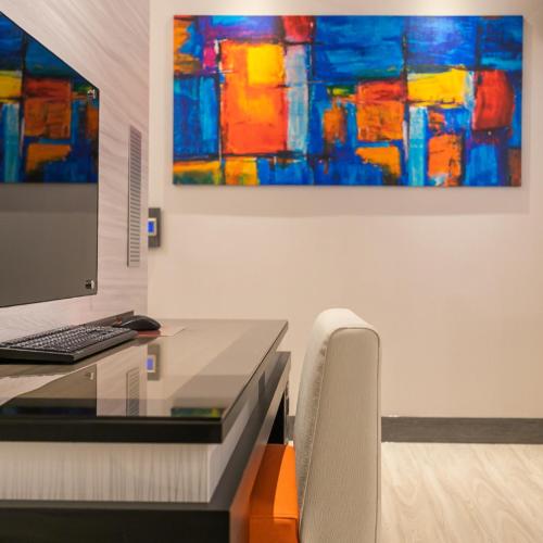 a desk with a computer and a painting on the wall at Soho Motel in Taoyuan