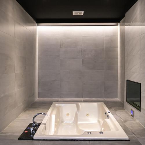 a white bath tub in a room with a tv at Soho Motel in Taoyuan