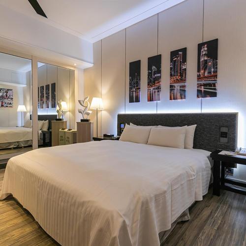 a bedroom with a large white bed and a desk at Soho Motel in Taoyuan