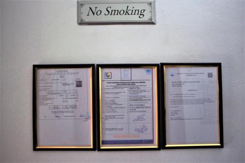 three framed signs on a wall with a no smoking sign at Pauls Retreat Wayanad in Wayanad