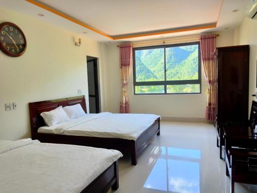 a bedroom with two beds and a clock on the wall at Khách Sạn - Nhà Hàng So Oanh - Gần Thác Bản Giốc in Cao Bằng