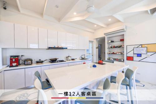 a white kitchen with a white table and chairs at 蒙德里安山水民宿 in Magong