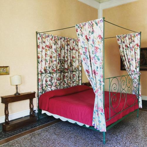 a bedroom with a canopy bed with red sheets at Palazzo Tucci Residenza d'epoca in Lucca