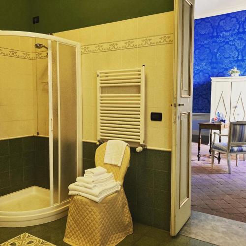 a bathroom with a shower and a chair with towels at Palazzo Tucci Residenza d'epoca in Lucca