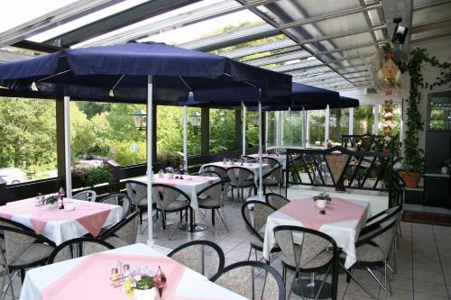 ein Restaurant mit Tischen und Stühlen und blauen Sonnenschirmen in der Unterkunft Hotel Ludwigstal in Schriesheim
