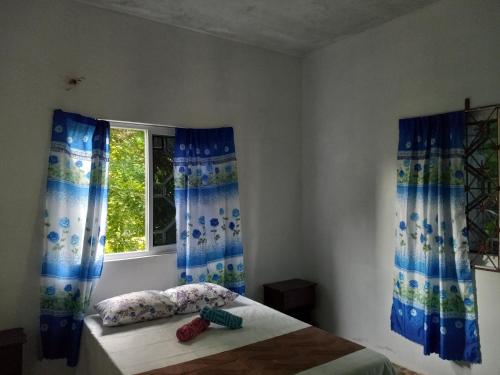 a bedroom with a bed with blue curtains and a window at The Gibson's Palace in Ocho Rios