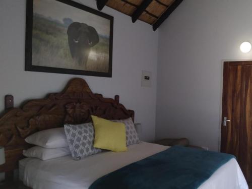 a bedroom with a bed with a wooden headboard and pillows at Caprivi River Lodge in Katima Mulilo