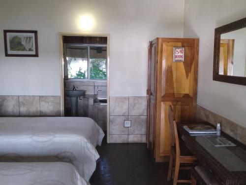 a bedroom with two beds and a bathroom with a sink at Caprivi River Lodge in Katima Mulilo