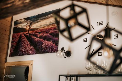 a clock on a wall with a picture of a field at Lawendowy Zakręt in Ustrzyki Dolne