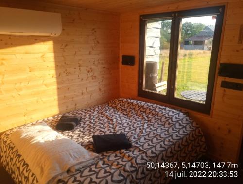 łóżko w pokoju z oknem w obiekcie Cabane de l'Ermitage w mieście Lessive