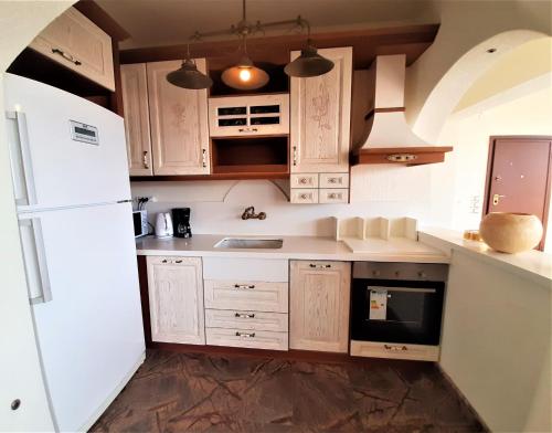 a kitchen with wooden cabinets and a white refrigerator at Royal stylish view apartment in Koropíon