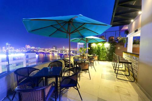 a patio with tables and chairs and umbrellas at night at Val Soleil Hotel in Da Nang