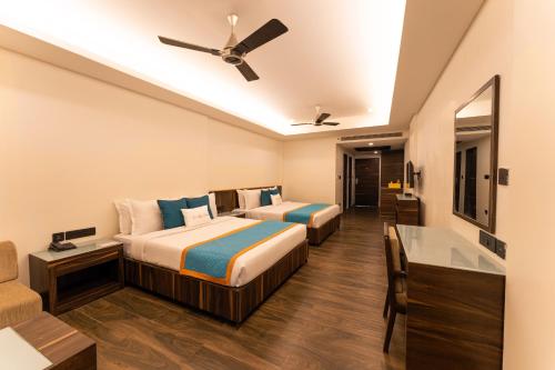 two beds in a hotel room with a ceiling fan at Zone Connect by The Park Parra Goa in Anjuna