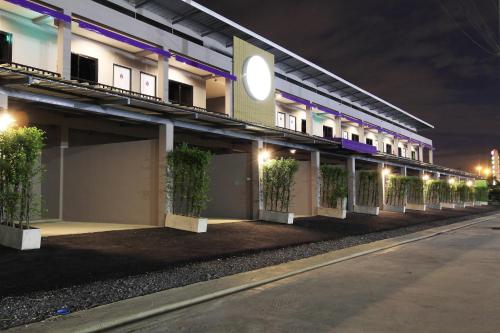 um edifício com plantas de lado à noite em Eazy Motel B.a.n.g.n.a em Samutprakarn