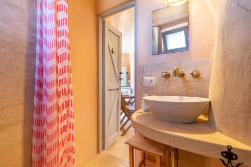 une salle de bain avec un lavabo et un miroir dans l'établissement Trulli Colle Specchia Intera Villa, à Cisternino