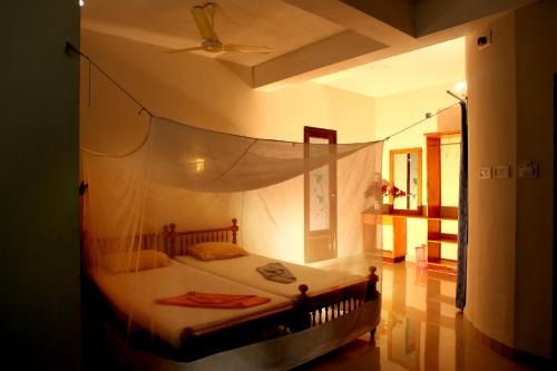 a bedroom with a bed with a mosquito net at Hotel Peacock in Kovalam