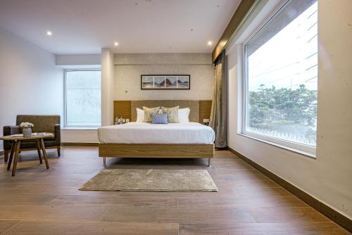a bedroom with a bed and a large window at The Sulit Whitefield in Bengaluru