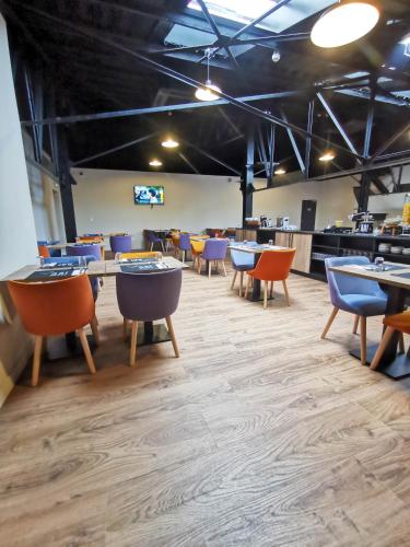 a dining room with tables and chairs and a kitchen at Aux Ateliers in Miserey-Salines