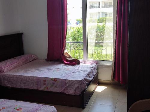 een slaapkamer met een bed en een raam met roze gordijnen bij palmera el sokhna in Suez