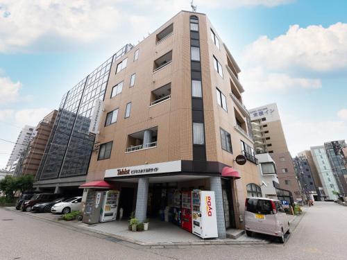 a tall building with a van parked in front of it at Tabist Business Hotel R Side Kanazawa in Kanazawa