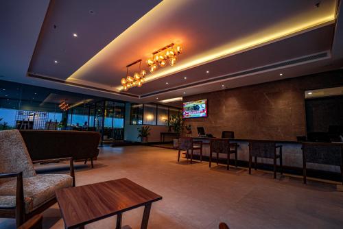a lobby with chairs and tables and a television at The Sulit Whitefield in Bengaluru