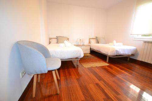 ein Zimmer mit 2 Betten und einem Stuhl darin in der Unterkunft Apartamento Andoaga in San Sebastián