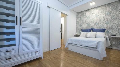 a bedroom with a white bed with blue pillows at La Casa de San Miguel by Toledo AP in Toledo